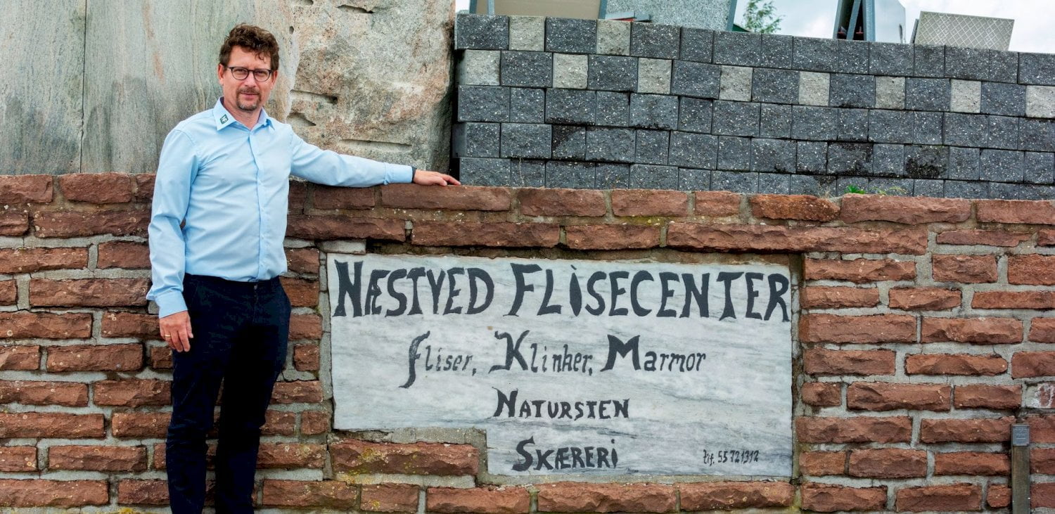 Medarbejder ved det gamle skilt fra Næstved Flisecenter med fliser, klinker, marmor, natursten og skæreri