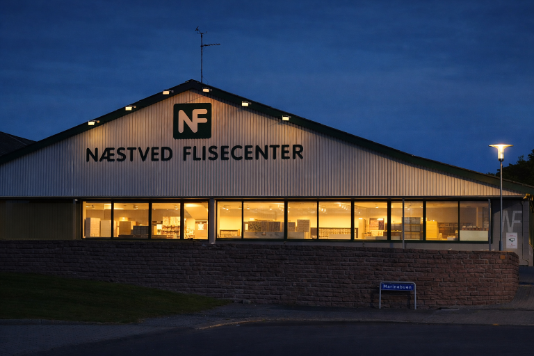 Næstved Flisecenter om aftenen med lys i vinduerne